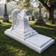 Marble weeping angel monument and ledger shown down a cemetery avenue