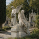 Marble standing angel memorial shown with a companion piece in a cemetery