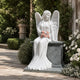 Marble seated angel garden statue shown beside a gravel garden path