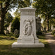 Marble angel and mourner monument shown on a cemetery avenue