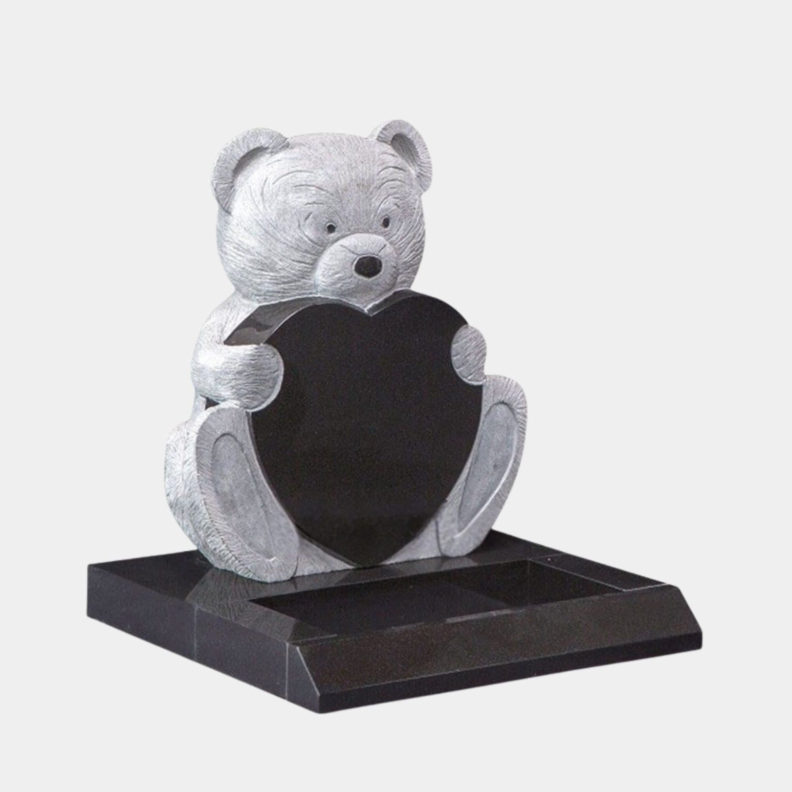 Black granite child memorial with a pale bush-hammered bear holding a polished heart, 100cm