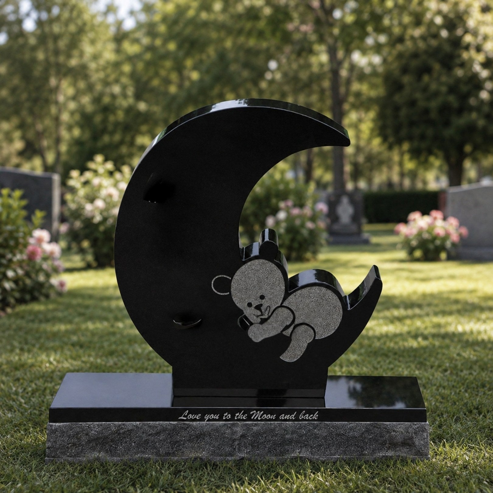 Black granite moon and bear child memorial shown on a cemetery lawn