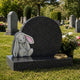 Grey granite toy rabbit child memorial shown on a cemetery lawn