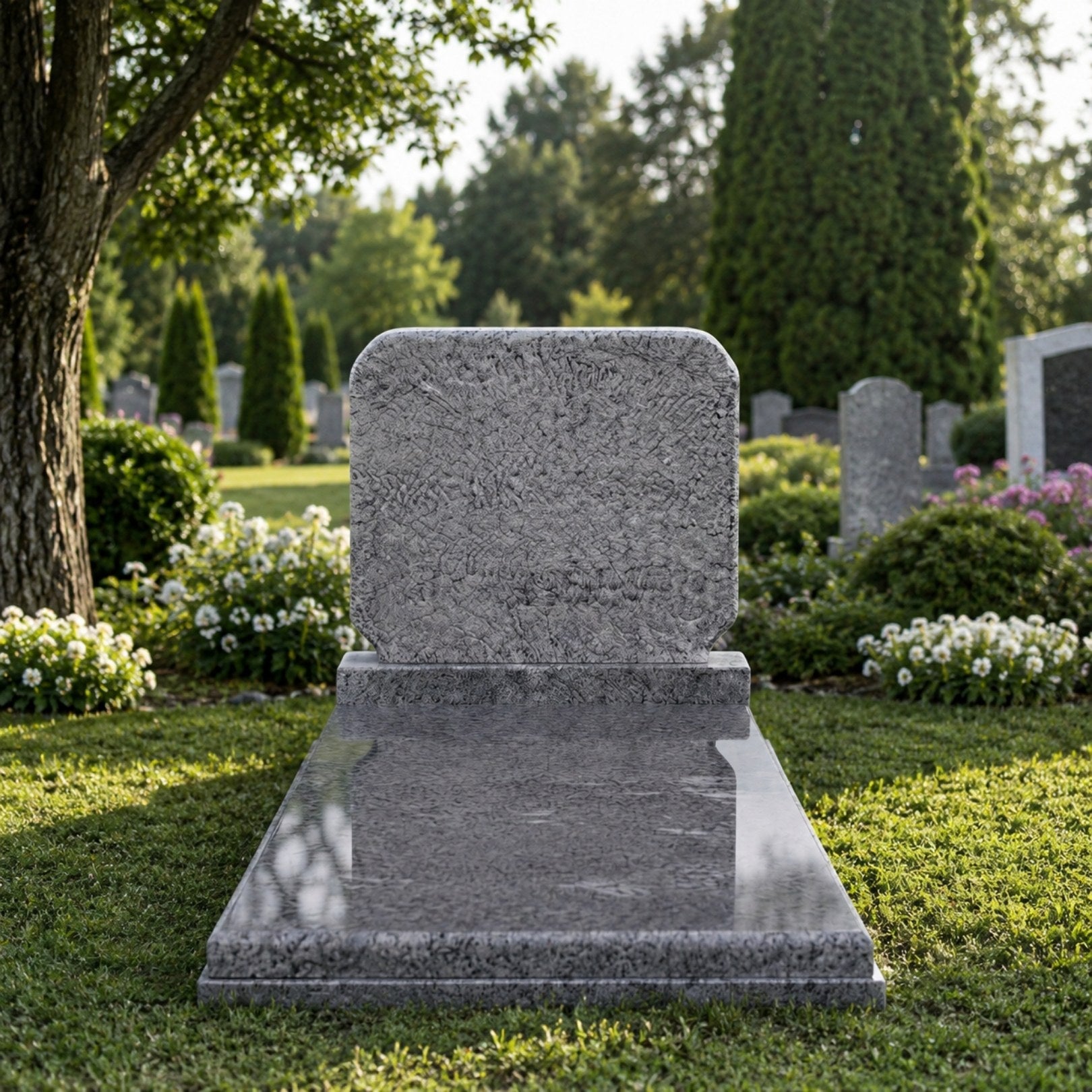 Grey granite pitched tablet and polished ledger memorial shown on a lawn