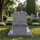 Grey granite pitched tablet and polished ledger memorial shown on a lawn