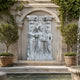 Three women gathering roses marble group shown on a formal garden axis