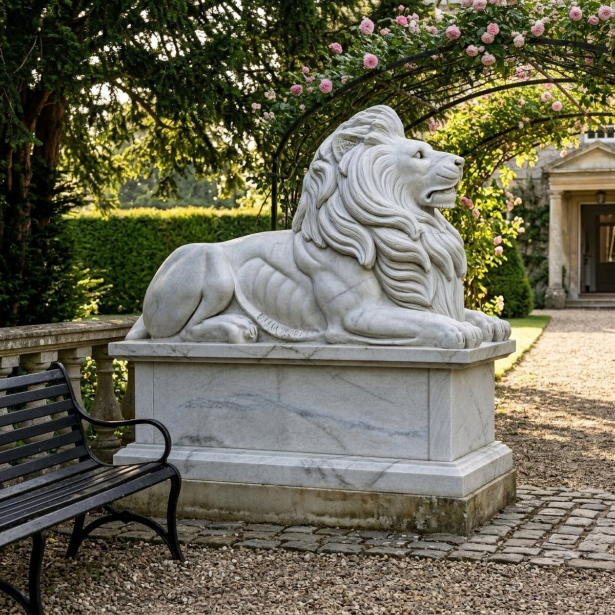 Couchant Lion on a Tall Pedestal Marble Statue - 180cm, white marble lion with flowing mane on a stepped pedestal, shown in a garden setting near a bench and rose arch.