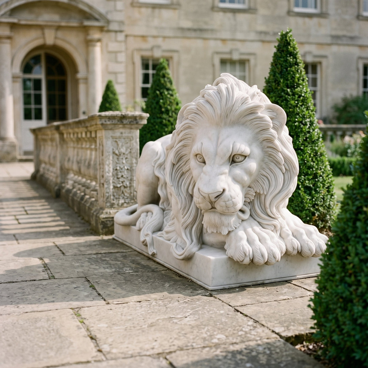 Couchant Lion With Paws Over the Edge Marble Statue - 105cm, white marble lion with crossed forepaws on a stepped plinth, set on a stone terrace beside a manicured hedge.