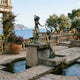 Monumental Classical Dual Mermaid Bronze Sculpture by Giant Sculptures on a stone plinth fountain, overlooking a Mediterranean coastline with terracotta pots.