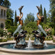 Mirrored view of the Monumental Classical Mermaid and Dolphin Bronze Sculpture by Giant Sculptures in a rose garden fountain, dual-tone bronze and verdigris finish.