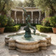 Monumental Classical Mermaid with Dolphins Bronze Fountain by Giant Sculptures in verdigris patina, mermaid lifting a dolphin overhead above a carved stone basin in a colonnaded garden courtyard.