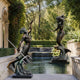 Monumental Classical Triton and Mermaid Bronze Sculpture by Giant Sculptures, bearded Triton with trident facing mermaid across a garden reflecting pool.
