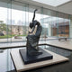 Giant Sculptures' 260cm Monumental Contemporary Dancing Female Figure Bronze Sculpture arched backward on a granite plinth in a glass gallery beside a rock garden.