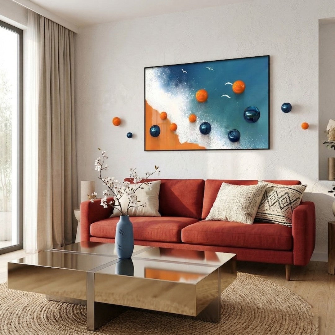 Tideborne Blue & Orange Coastal Horizontal 3D Wall Art with glossy orange and deep blue metal balls extending from a beach-and-wave canvas, displayed above a red sofa in a modern living room.