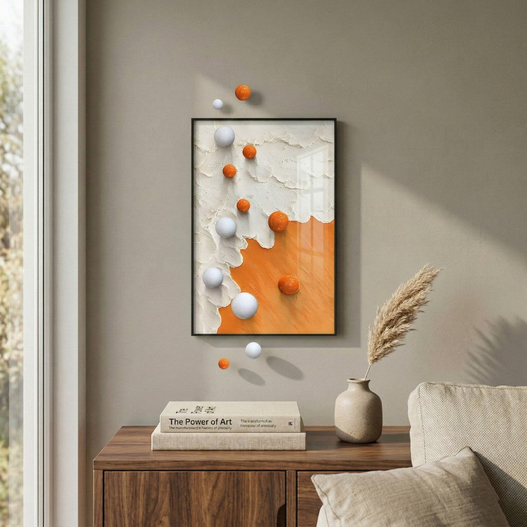 Tideborne White & Orange Texture 3D Wall Art With Metal Balls by Giant Sculptures displayed in a living room above a walnut sideboard, featuring layered white plaster-like texture, smooth orange lower section, and glossy white and orange metal spheres extending beyond the aluminium frame.