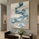 Aqualoom I Layered Leather Hand-Painted 3D Wall Art by Giant Sculptures displayed in a neutral-toned hallway, showing flowing teal and pale aqua leather disc clusters on a beige textured canvas above a brown velvet bench.