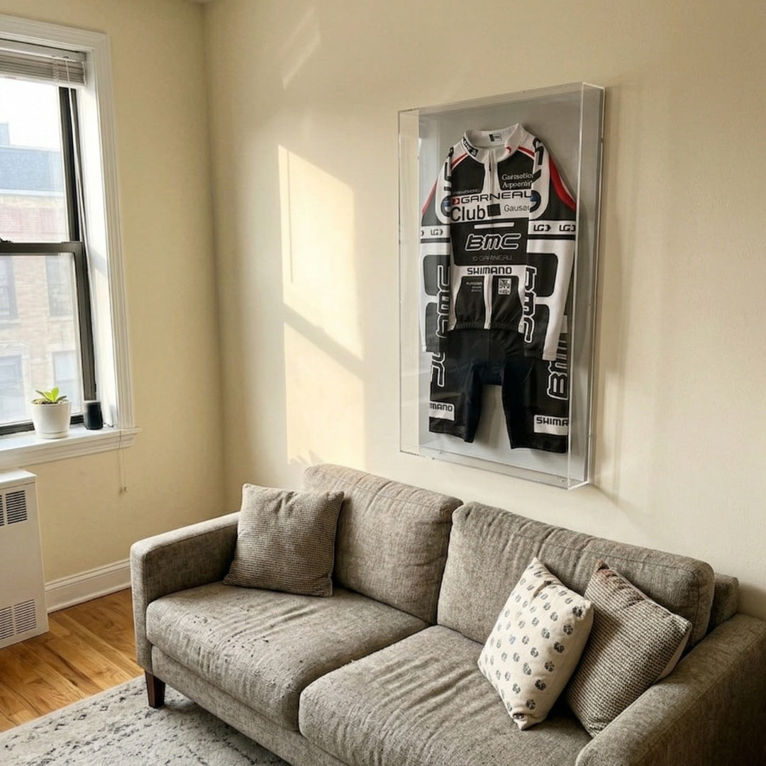 Giant Sculptures Apexline Motorsport Racing Suit Acrylic Box 3D Wall Art in black and white with red accents, mounted above a grey sofa in a sunlit living room.