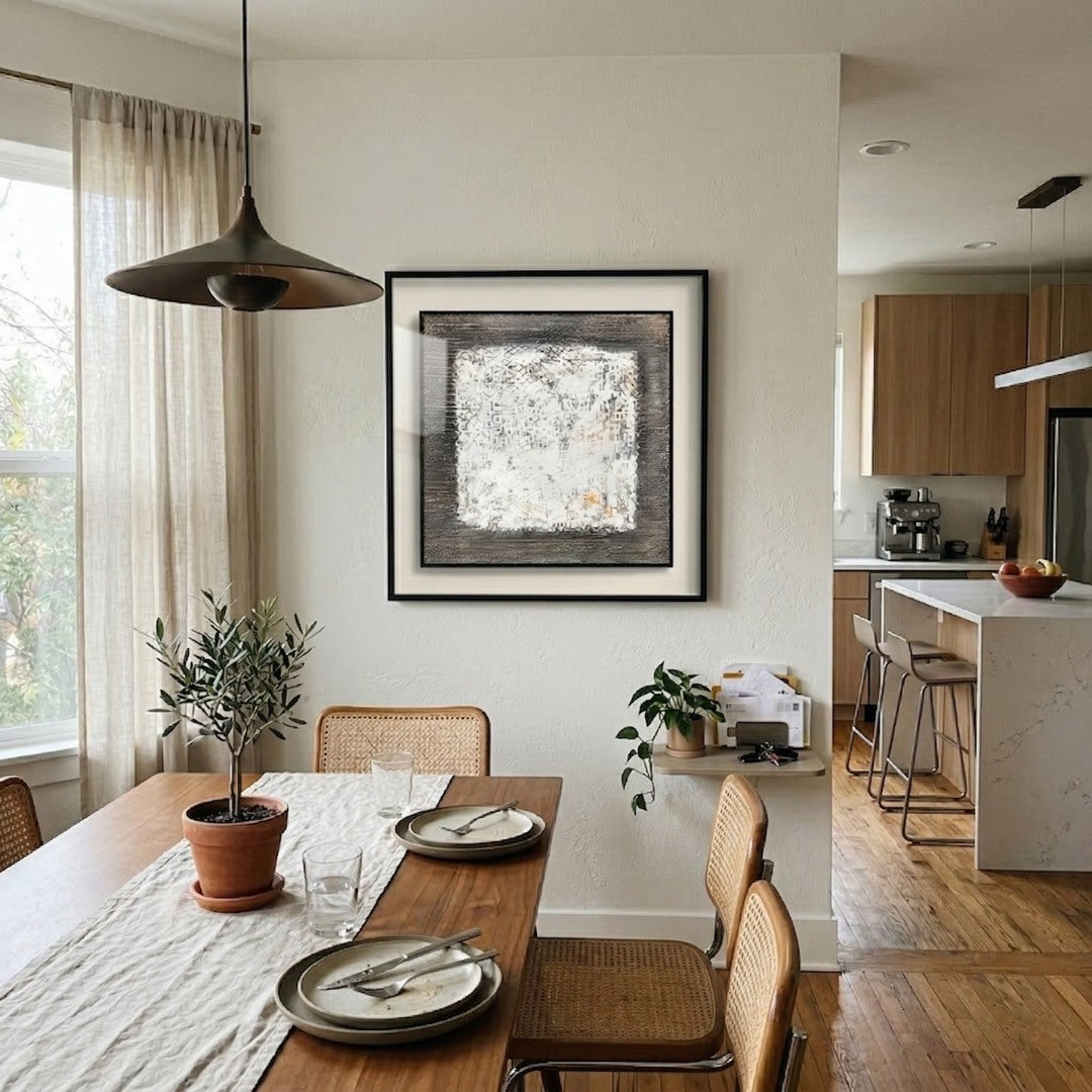 Tracera White Distressed Block Abstract Textured Framed Wall Art by Giant Sculptures displayed in a neutral dining room above a wooden table with cane chairs and an open kitchen beyond.