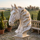 Horse Head Bust with Flowing Mane Marble - 180cm in white marble on a pedestal, shown outdoors on a stone terrace with a countryside and castle view.