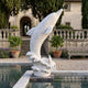 White marble Leaping Dolphin on a Wave Statue, 180cm, poolside on a villa terrace with balustrade, potted citrus trees, and stone steps behind.