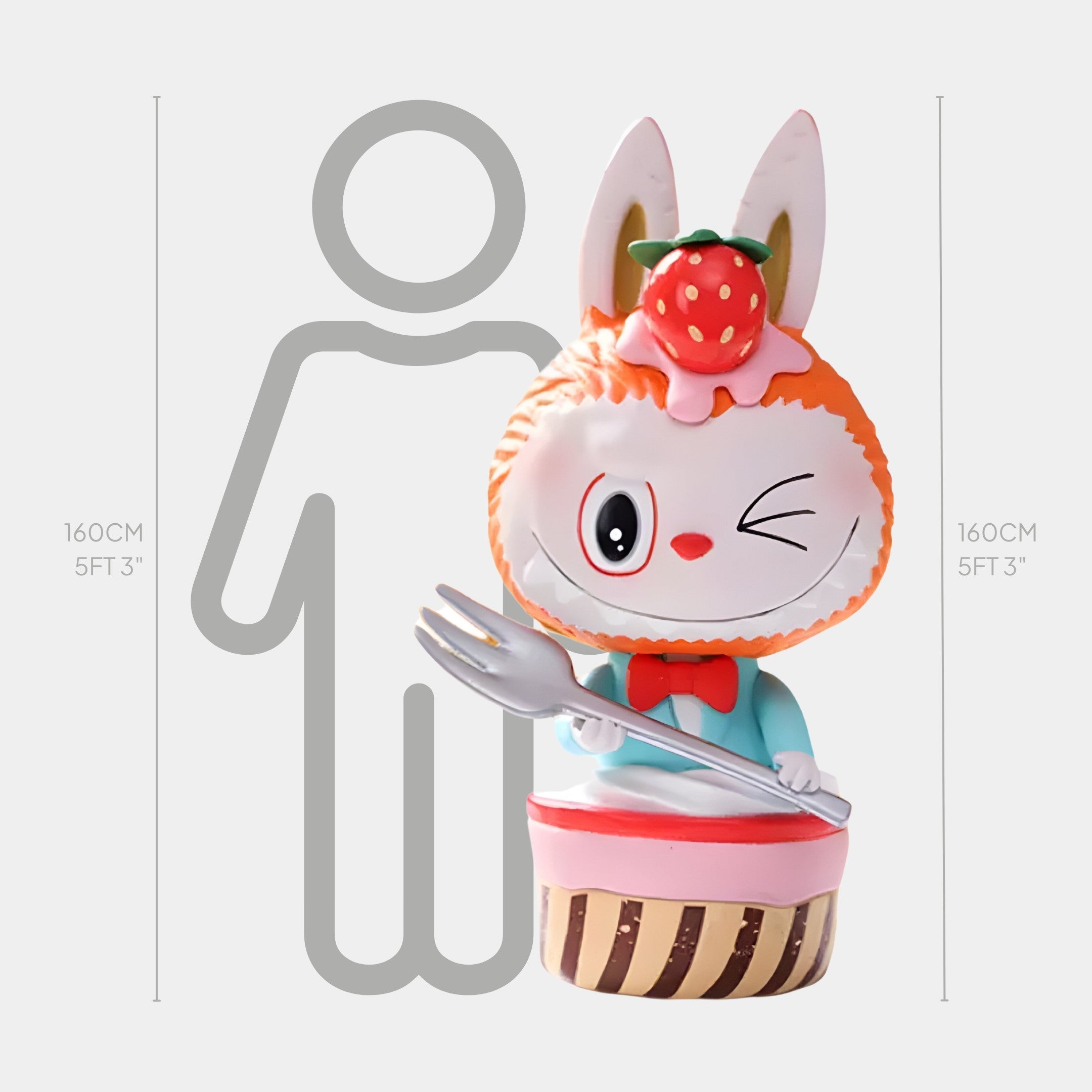 The Sweet Mischief Strawberry Wink Labubu Sculpture by Giant Sculptures features a rabbit with a strawberry on its head, sitting on a cupcake and holding a large fork, displayed beside a 160cm human height chart.