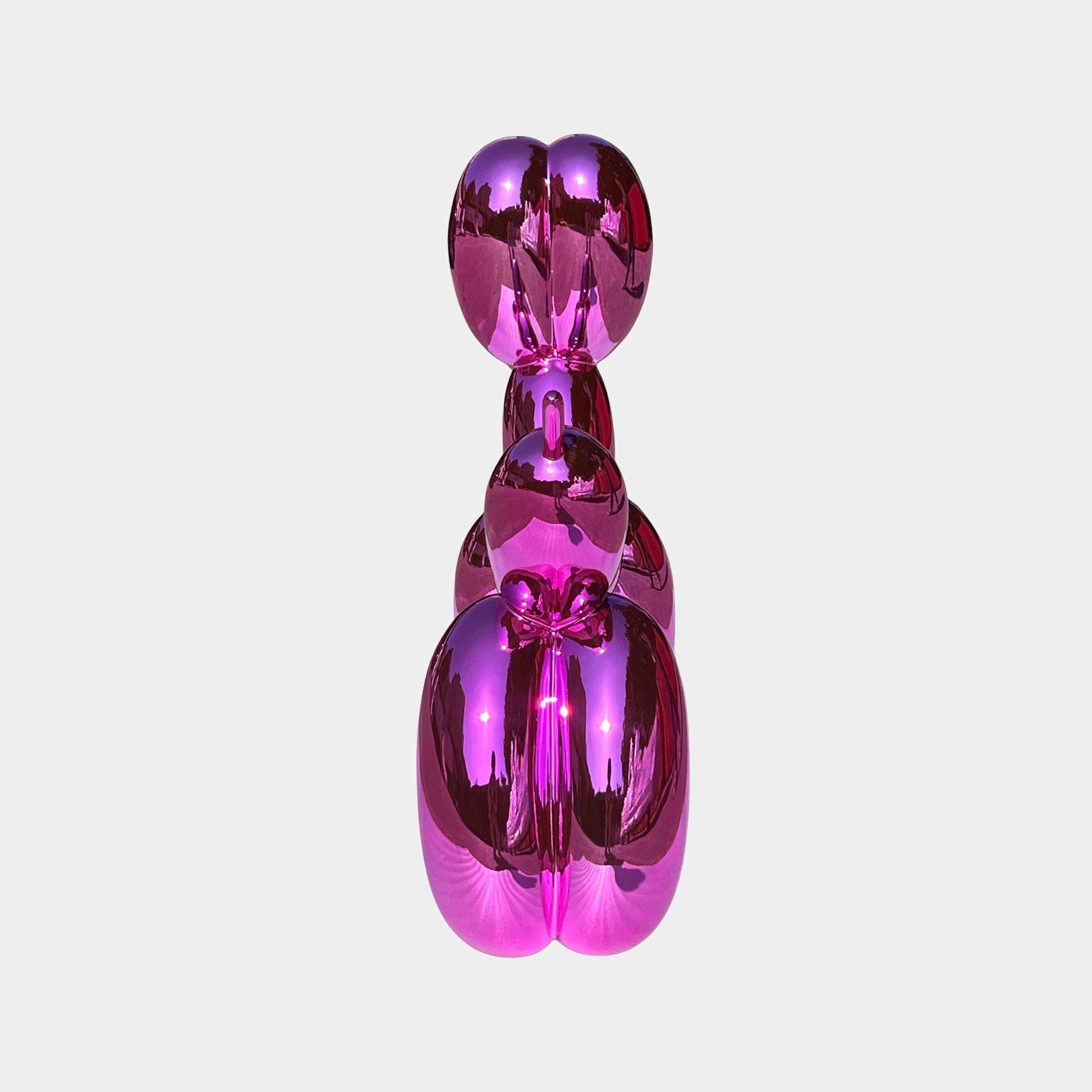 The Flamingo Pink Balloon Dog Sculpture - 80cm by Giant Sculptures gleams with a modern, reflective finish, making it a bold centerpiece that captures contemporary art’s playful flair against any plain background.