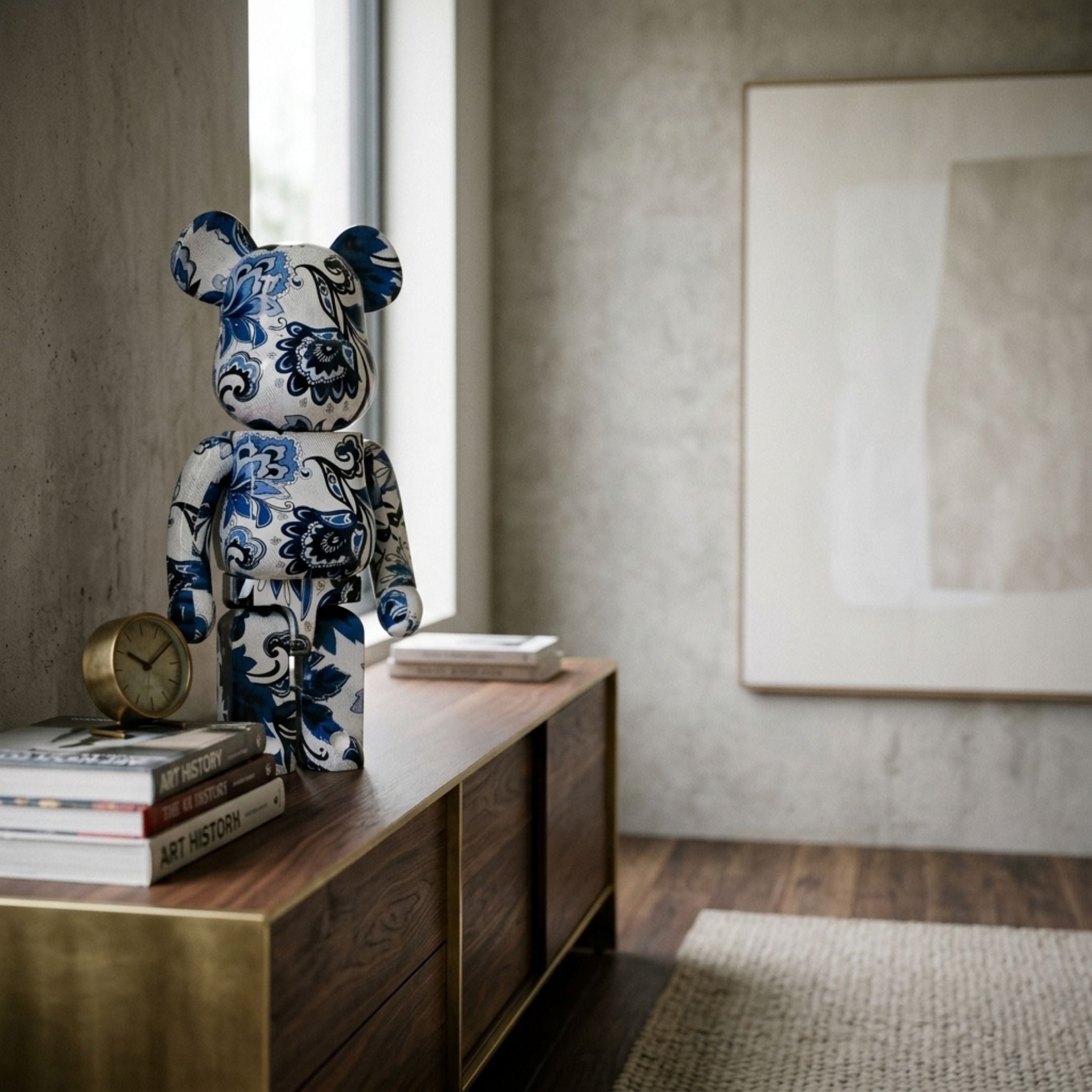 Porcelain Art Bear Sculpture - 70cm with cobalt-blue floral motifs on white, displayed on a wood console beside a clock and books near a window.