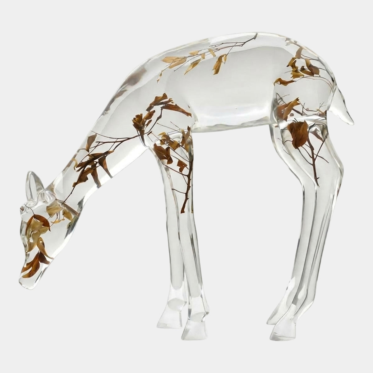 Clear Grazing Hind with Suspended Leaves - 106cm, a clear resin deer sculpture with head lowered, dried leaves and twigs embedded throughout, on a plain white background.