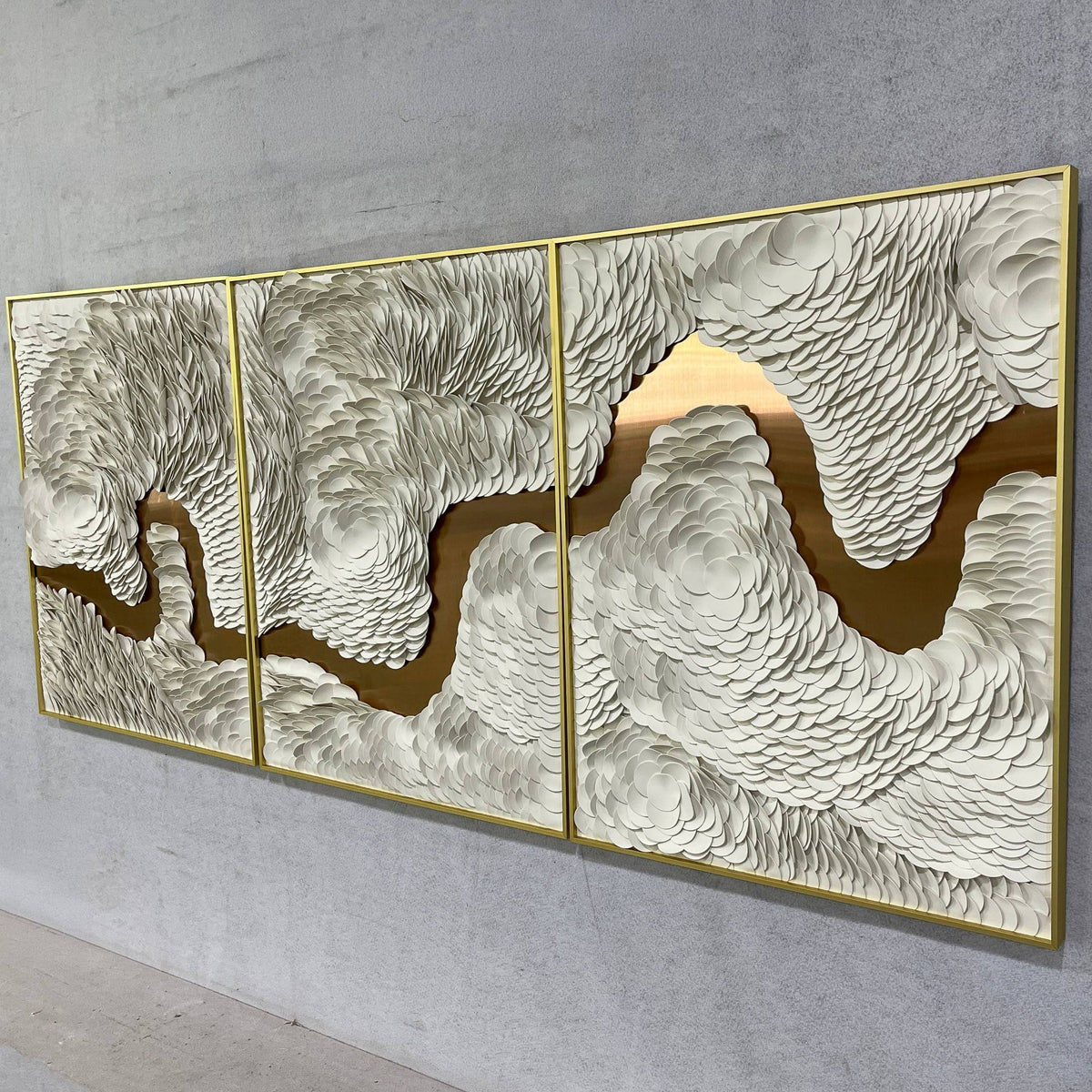 Riverine Flow Pearl White Textured Triptych Wall Art by Giant Sculptures, three gold-framed panels with raised pearl-white texture over a gold metallic background, mounted on a grey wall.