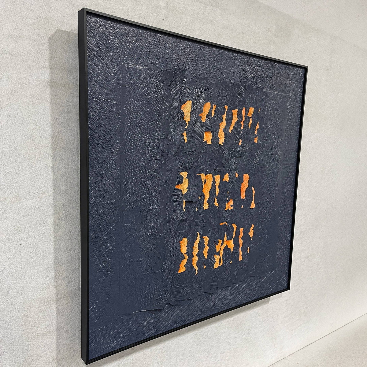 Rivura Navy Layered Sandstone Texture 3D Wall Art in a black frame, torn navy strips revealing orange and beige layers, mounted on a light wall, side angle view.