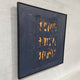 Rivura Navy Layered Sandstone Texture 3D Wall Art in a black frame, torn navy strips revealing orange and beige layers, mounted on a light wall, side angle view.