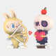 Two adorable figurines: Giant Sculptures’ Spooky Buddies Cupid Chaos Labubu Sculpture (100cm), a yellow bunny with heart bow, and a skeleton in a dress holding a pink heart, apple on its head, and swirly eyes.