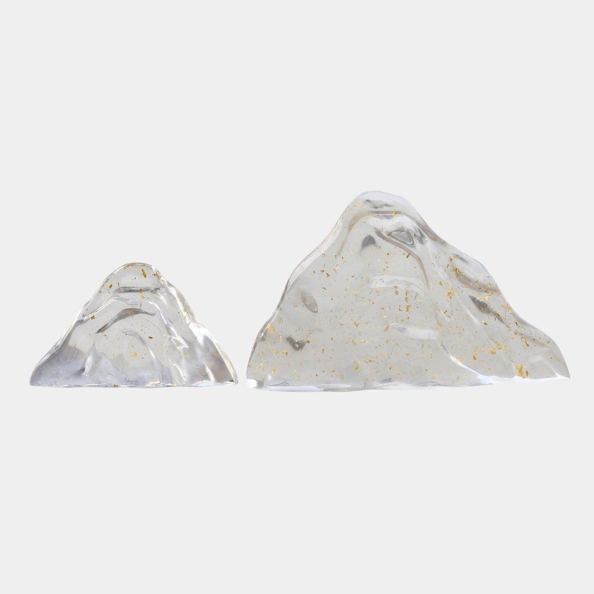 Clear Gold Leaf Mountain Ranges Resin Sculpture Set of Two, two peaked clear resin mountains with gold leaf flecks, on flat bases against a plain white background.