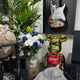 A decorative space featuring a globe, a vase of white lilies and blue roses, lush green plants, the Giant Sculptures Slam Icon Bear Sculpture - 70cm in a Chicago #23 jersey, and a vibrant electric guitar mounted on the wall.