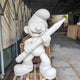Unpainted white fibreglass Giant Pencil Smurf Standing Sculpture 150cm in primer finish, holding an oversized pencil, displayed in a workshop on wooden pallets.