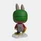 A cartoon-style figure with a green helmet and rabbit ears, red plaid shirt, gray backpack, yellow boots, and blue pants stands on snow—perfect for indoor winter fun with the Giant Sculptures Camp Life Snow Hiker Labubu Sculpture (100cm).
