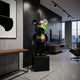Split Anatomy Black Bear Sculpture, 70cm, on a black plinth in a modern living room with a dark accent wall, TV console, and city-view windows.