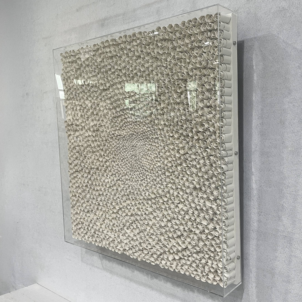 TerraLuma Ivory White Bloom Paper Craft 3D Wall Art, side angle view of coiled paper rosettes in a radiating pattern, framed in clear acrylic on a grey wall.
