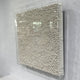 TerraLuma Ivory White Bloom Paper Craft 3D Wall Art, side angle view of coiled paper rosettes in a radiating pattern, framed in clear acrylic on a grey wall.