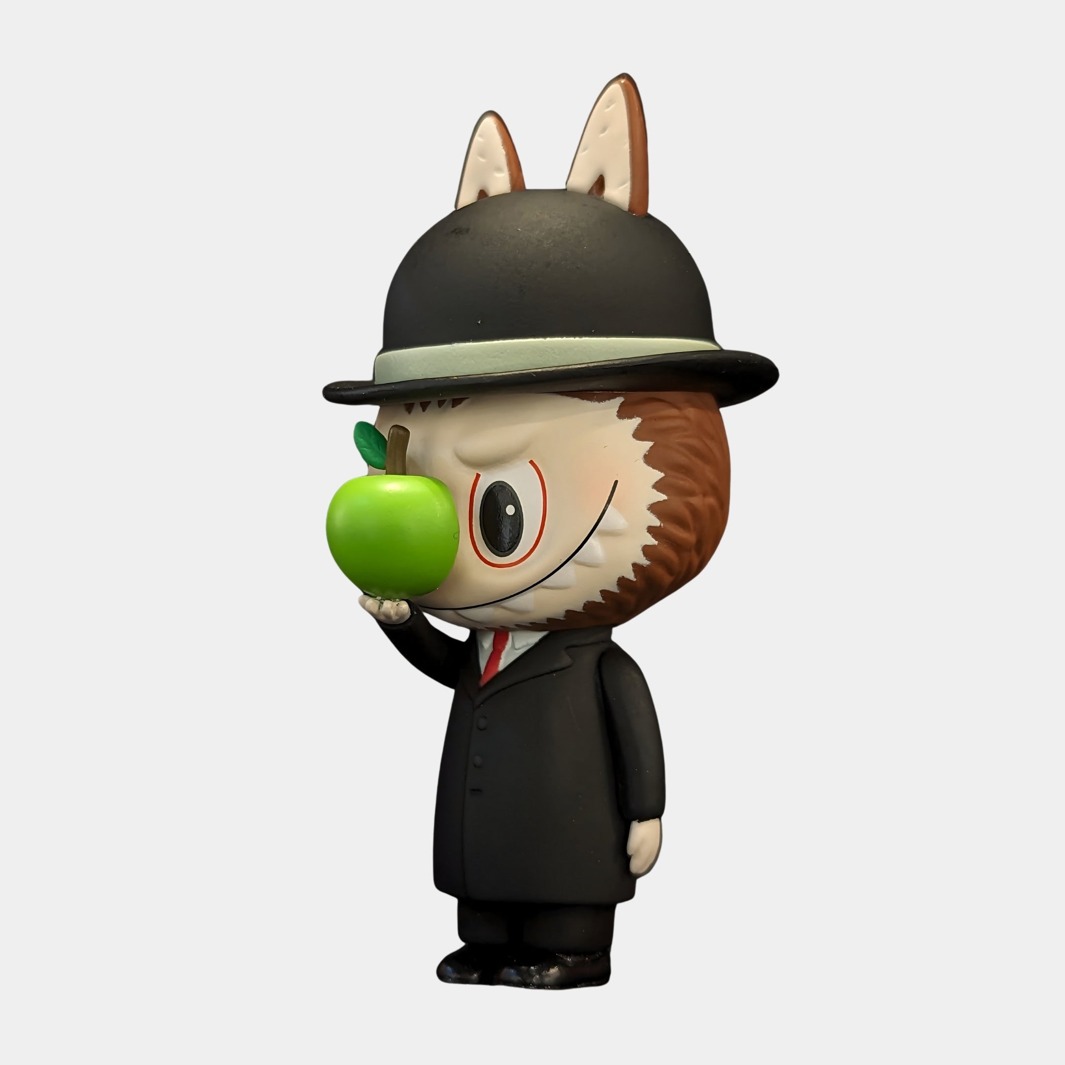 The Giant Sculptures Art History Apple Mystery Labubu Sculpture - 160cm features a cartoonish Labubu in a black suit and bowler hat, holding an apple before its face—an homage to René Magritte’s The Son of Man.