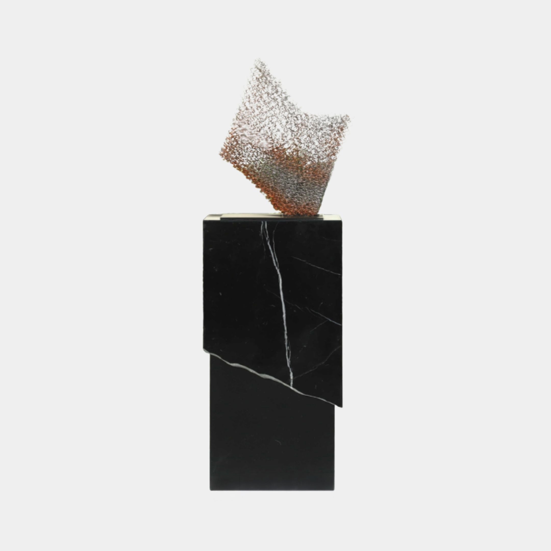 Silver and copper mesh abstract sculpture by Giant Sculptures, crumpled into a sail-like form atop a tall black marble monolith base with white veining.