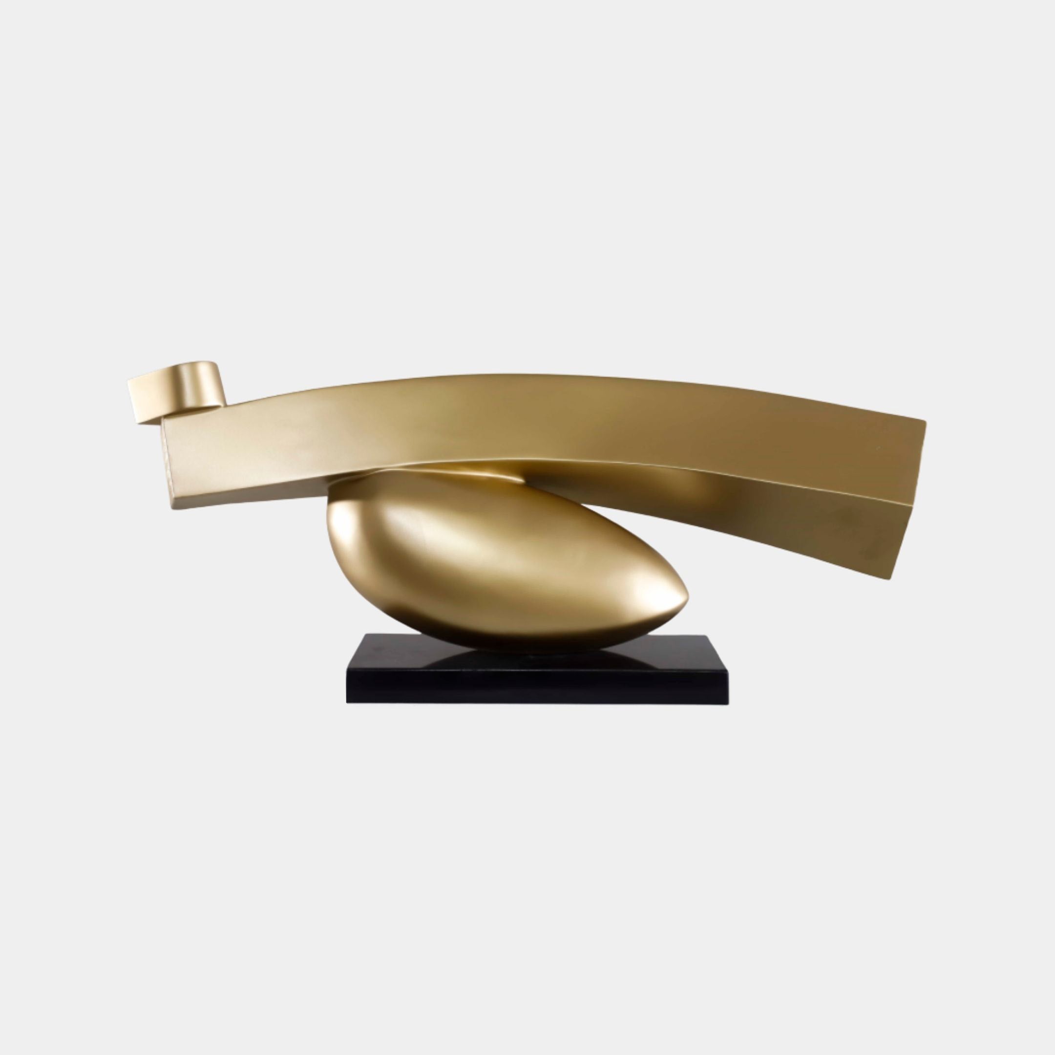 Giant Sculptures' 107cm Brushed Gold Abstract Curved Horizontal Metal Sculpture with an elliptical egg form beneath a sweeping blade on a black base.