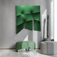 A modern interior features the Contours Emerald Green Elastic Fabric 3D Wooden Wall Art by Giant Sculptures, paired with two round ottomans—one green and one gray—and a glass coffee table with silver decor. A tall cactus by a sunlit window casts shadows on the white walls and floor.