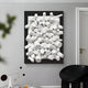 The Axion White Wood Cluster & Black Edge 3D Wall Art by Giant Sculptures features white cylindrical shapes in a black frame on a gray wall, complementing the rooms contemporary interiors with a black chair, patterned table, and small mobile sculpture.