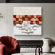 The Structura Terracotta & White 3D Wooden Square Wall Art by Giant Sculptures showcases modern craftsmanship with a grid of red and orange hues on a neutral background. Its layered, three-dimensional effect pairs beautifully with a red plush chair and white abstract chair nearby.