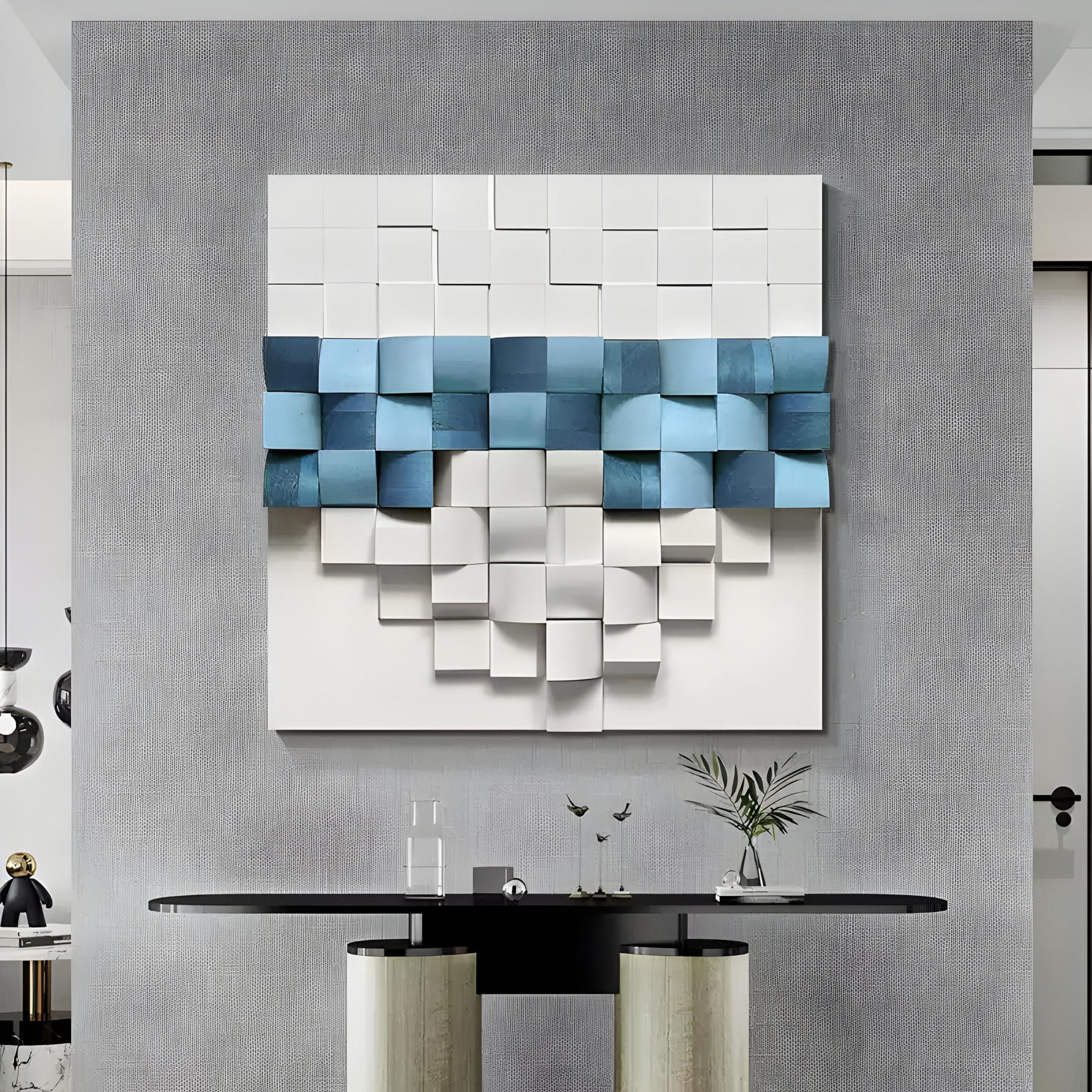 The Structura Azure Blue & White 3D Wooden Square Wall Art by Giant Sculptures brings Nordic minimalism with its geometric design of white and azure cubes. A sleek black console table below displays a small plant and sculptures, enhancing the minimalist decor.