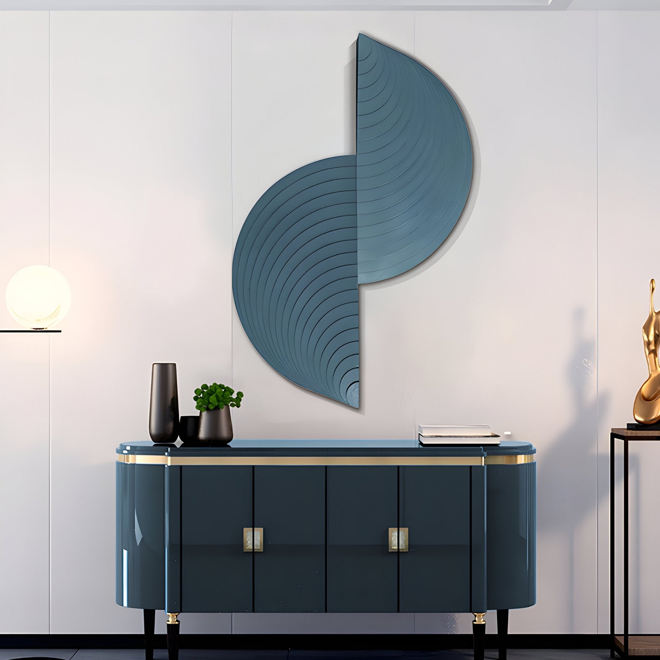 A modern interior showcases a sleek deep teal sideboard with gold accents, topped with a plant, vases, and books. Above it hangs the Orbitals by Giant Sculptures, an abstract blue 3D wall art with curved lines. A glowing spherical lamp is on the left and a golden sculpture on the right.