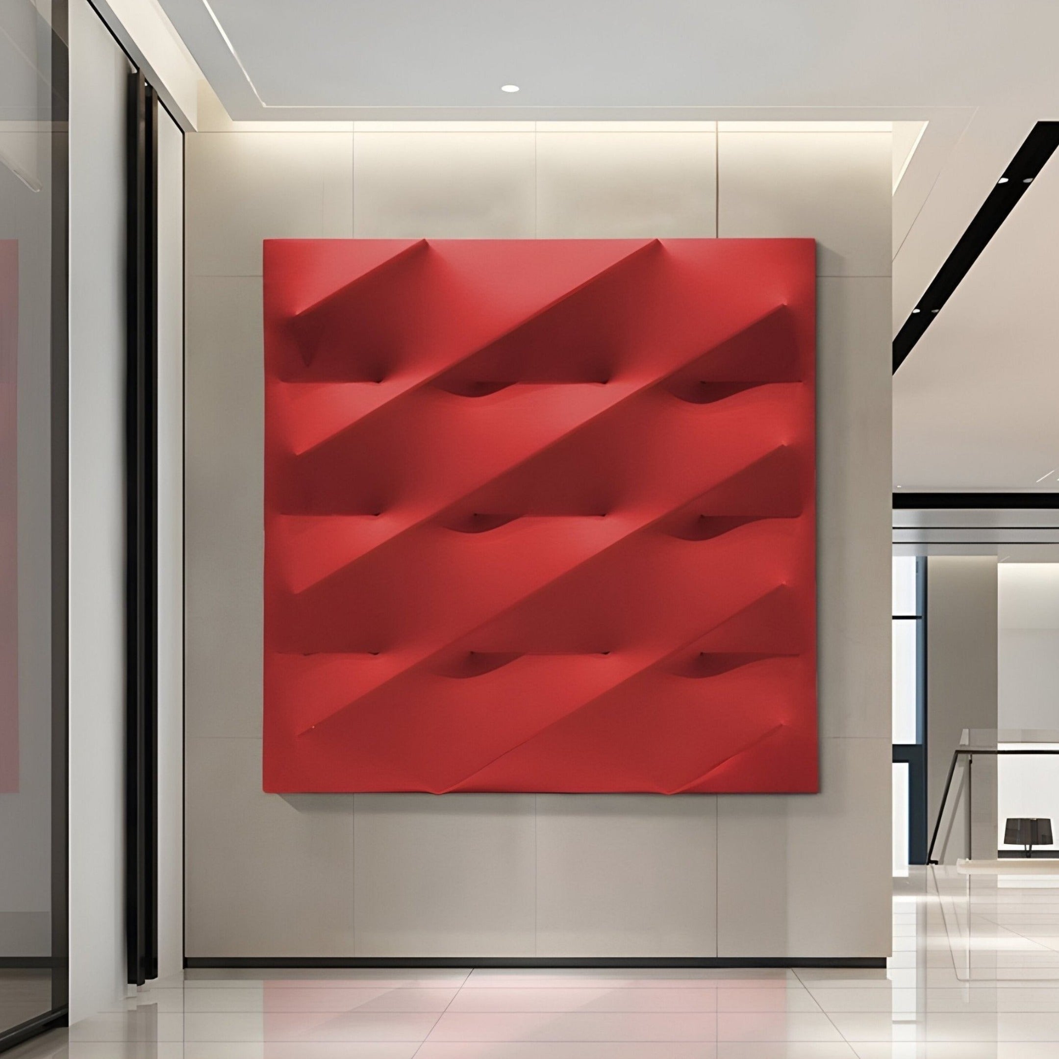 A minimalist room features a Verto Bold Red Stretch Fabric Layered Wooden 3D Wall Art by Giant Sculptures. Mounted on a light wall, the geometric piece forms a grid with diagonal, wave-like patterns that add shadows and texture as a striking centerpiece.