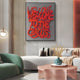 A modern living room showcases the Urbanic Red Welcome Script 3D Wooden Graffiti Wall Art by Giant Sculptures on a gray background, complemented by a green sofa, round pink coffee table, and decorative plant for an urbanic vibe.