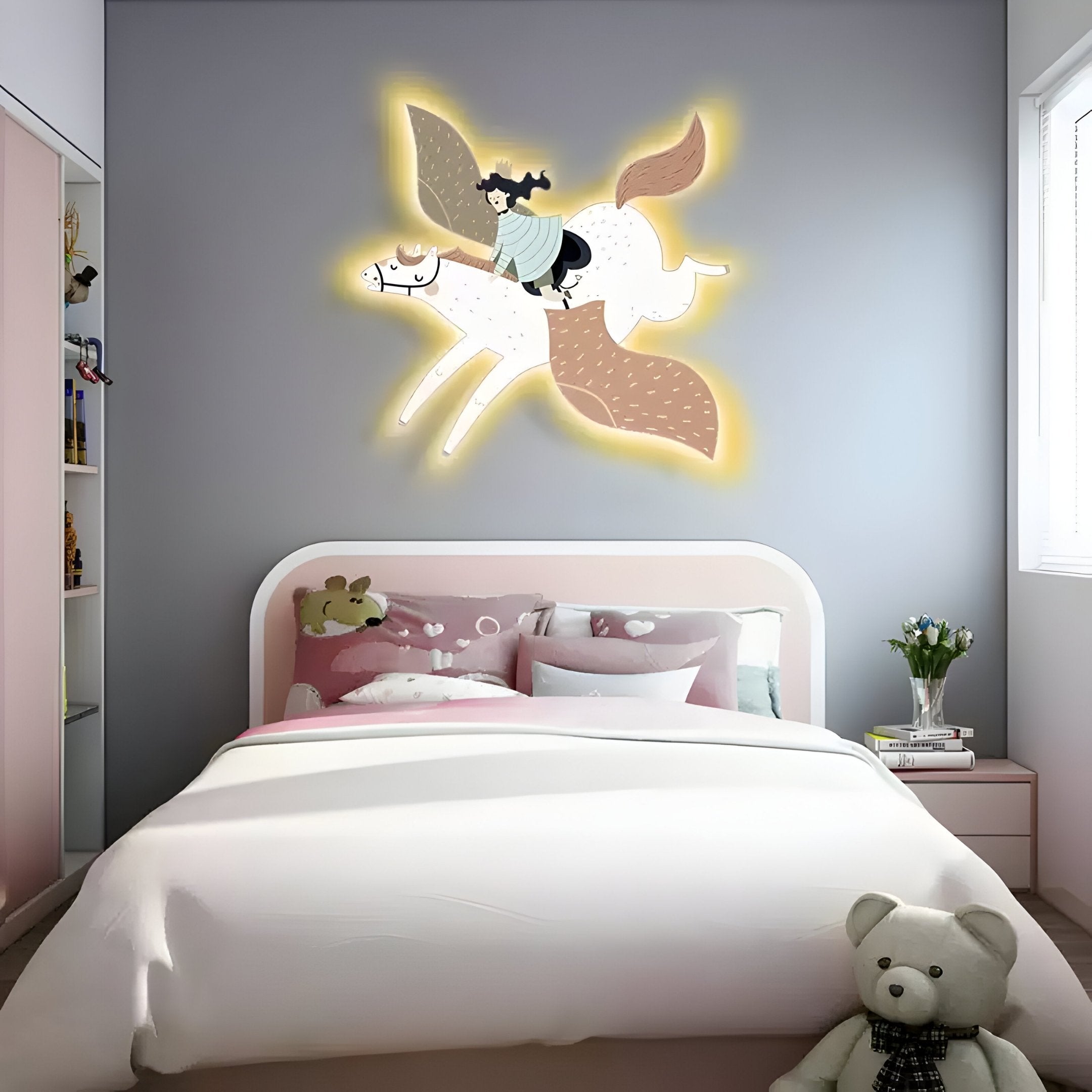 A dreamy childrens room features a pink bed, teddy bear, and flower vase. The wall displays Mythoria Journey Fairytale Horse Wooden LED Wall Art by Giant Sculptures. Shelves on the left and a window on the right let sunlight in, creating an enchanting atmosphere.